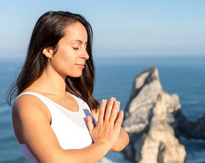 A woman meditates peacefully by the ocean in Portugal, embracing wellness.