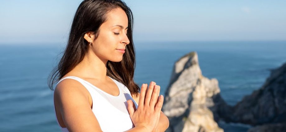 A woman meditates peacefully by the ocean in Portugal, embracing wellness.