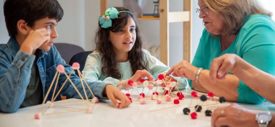 Grandmother playing educational games with grandchildren indoors, fostering creativity and learning.