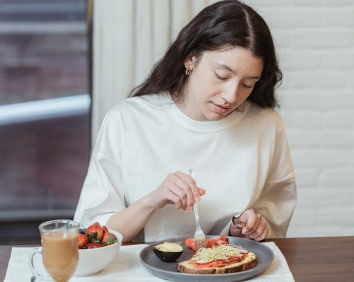 Woman having a nutritious breakfast with toast and strawberries in a cozy indoor setting.