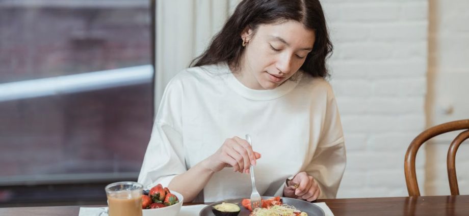 Woman having a nutritious breakfast with toast and strawberries in a cozy indoor setting.